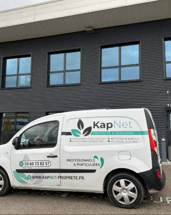 Camionnette blanche Kapnet Propreté devant un bâtiment noir.
