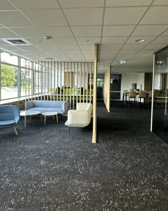 Locaux de bureau propre, réalisé par la société de nettoyage Kapnet Propreté. Canapé et chaise bleues dans un grand hall.